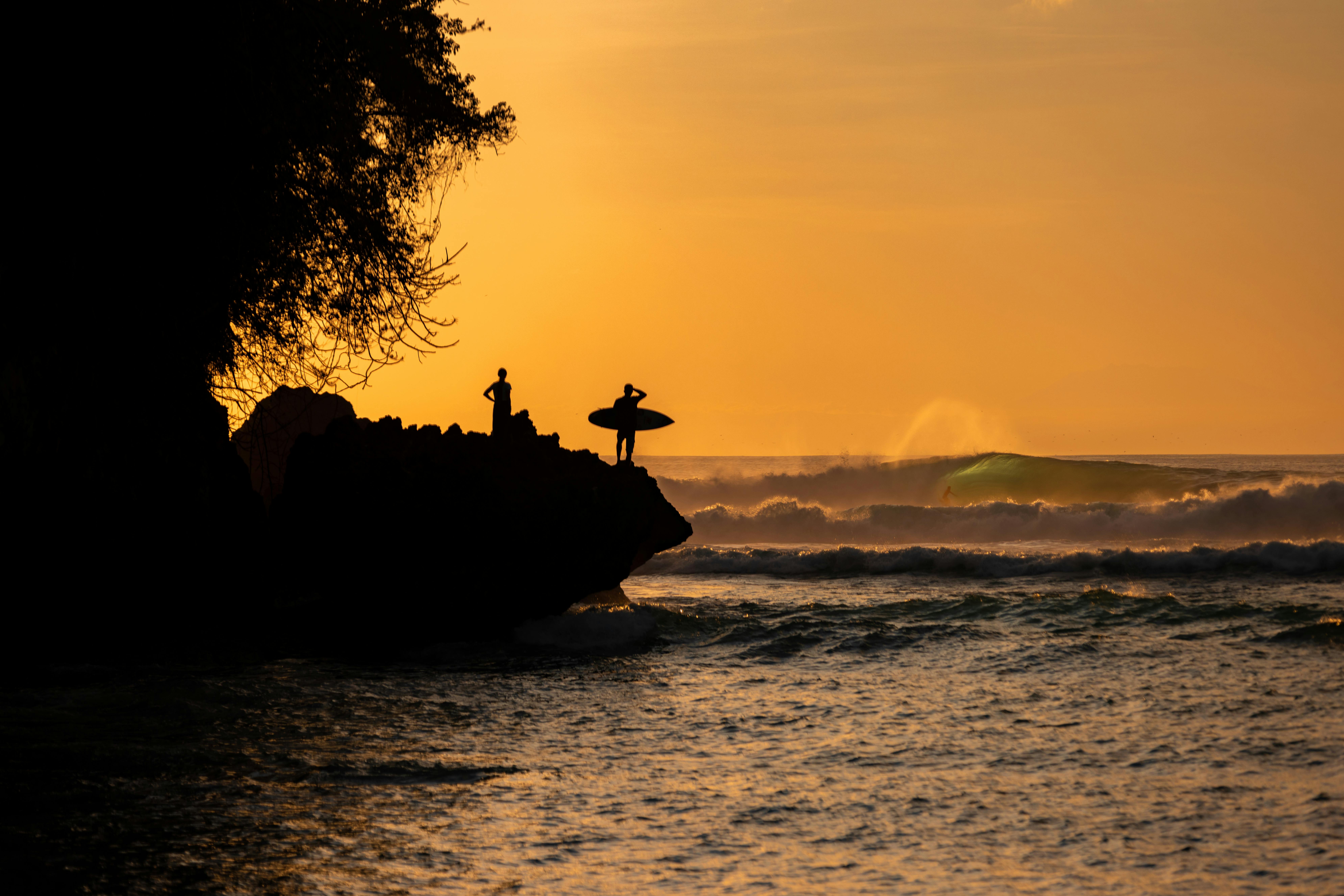 Surfers silhouetted at sunset on Bali coastline